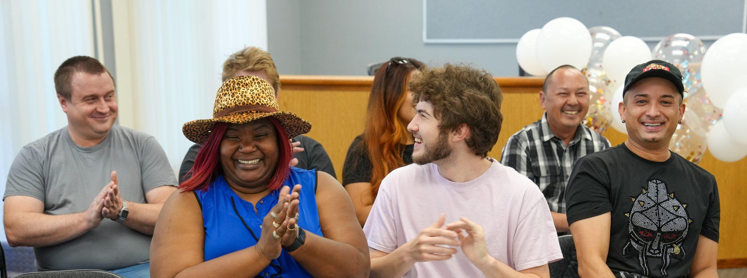 A group of community members laughing together while celebrating a program completion.